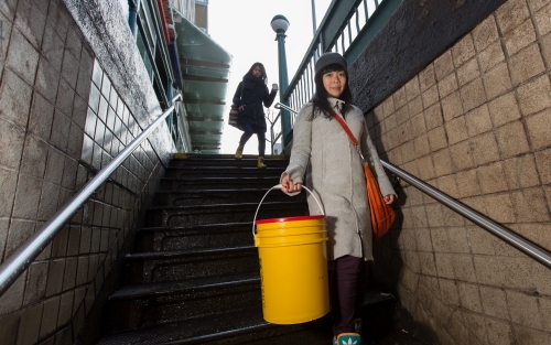 Rebecca Louie walks downstairs to a subway with a 5-gallon bucket of compost