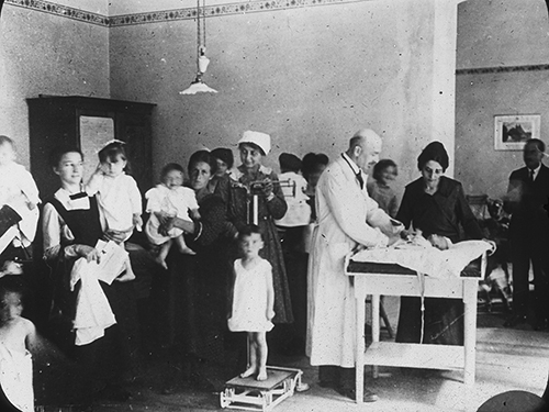 Archival photo of a doctor examining patients as part of the Quaker relief effort in Europe in 1919. 