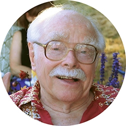 Irving Dayton, an older man with glasses and white hair looks at the camera. 