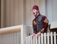 costumed male student orates while standing on a balcony