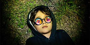 small person with glasses reclining on some grass