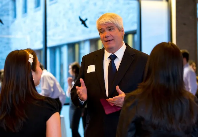 Man dressed in suit talking to two women at a Swarthmore alumni event