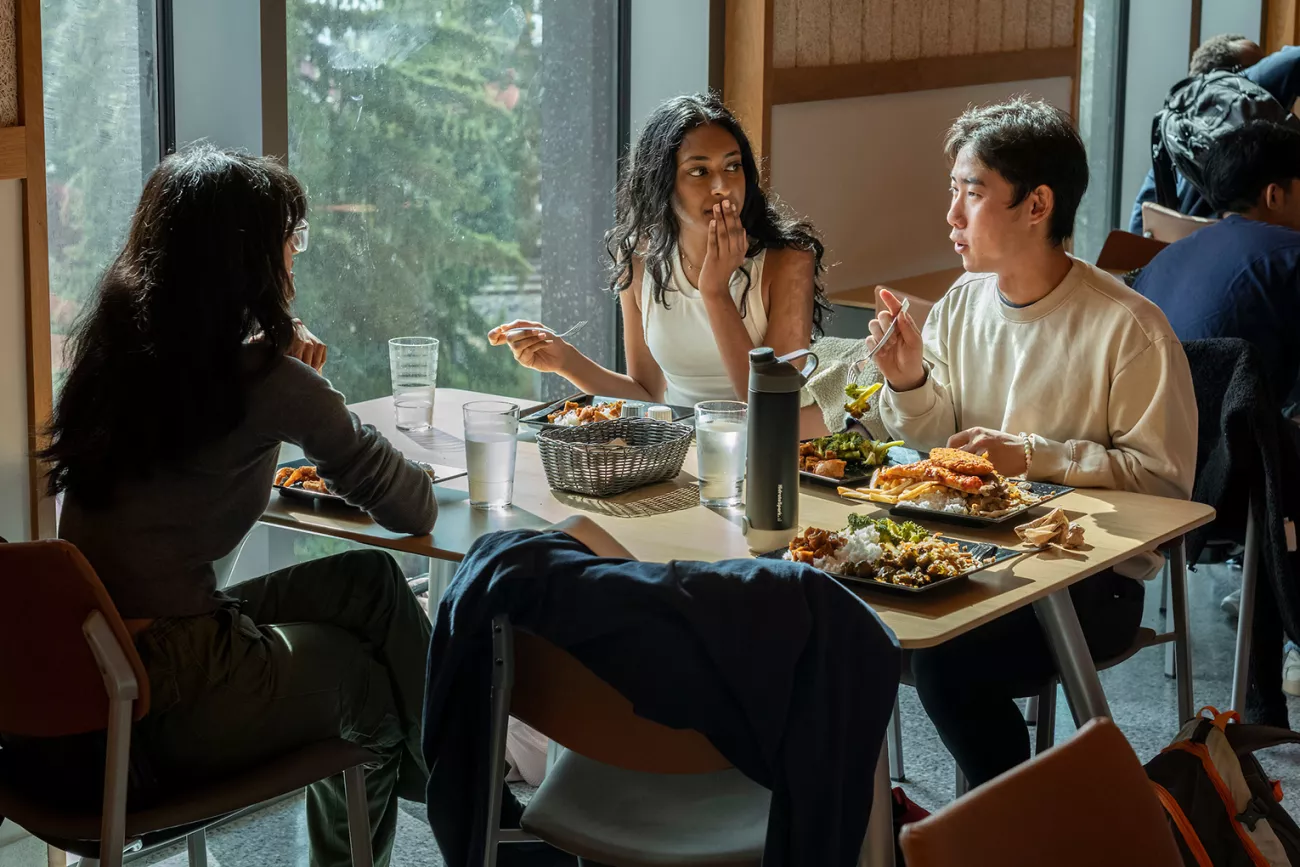 Students enjoy meal in dining center by window