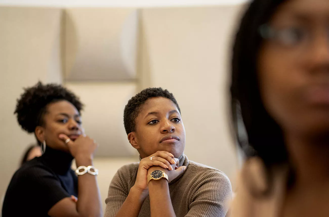 three students listening to a speaker