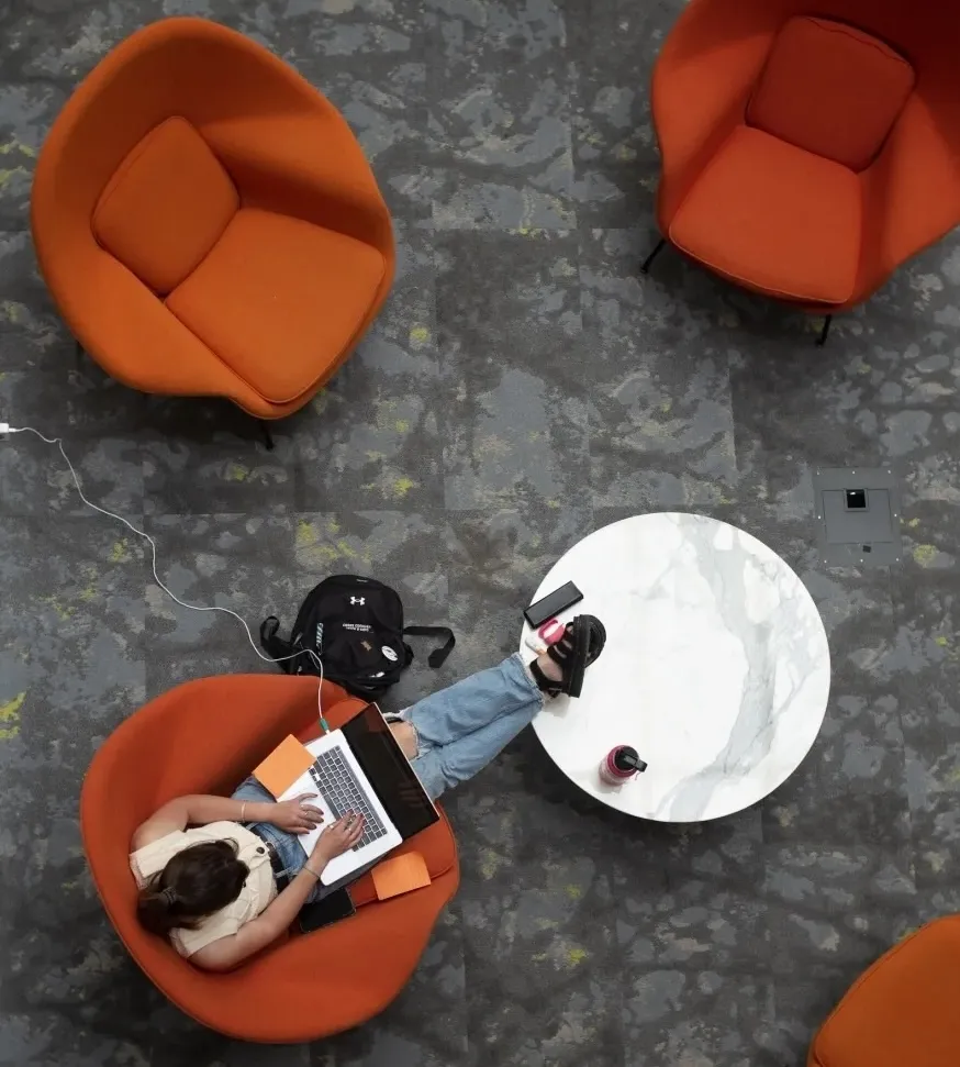 Top-down image of a student studying with a laptop on their lap