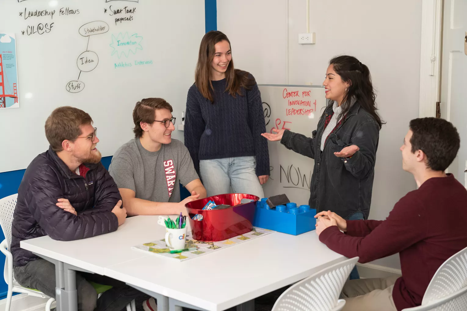 Students sit at table in front of whiteboard