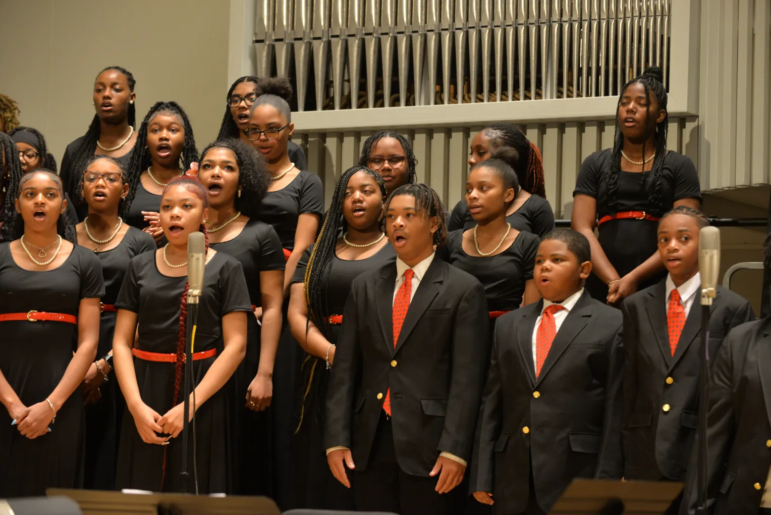 children in chorus singing wearing black dresses and black jackets