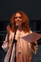 Portrait of Alma Richeh at a microphone holding a piece of paper