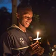 A student stands with his lit candle during First Collection