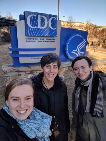 Three people pose in front of sign for Center for Disease Control