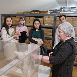 Woman shows group of student art installation under case