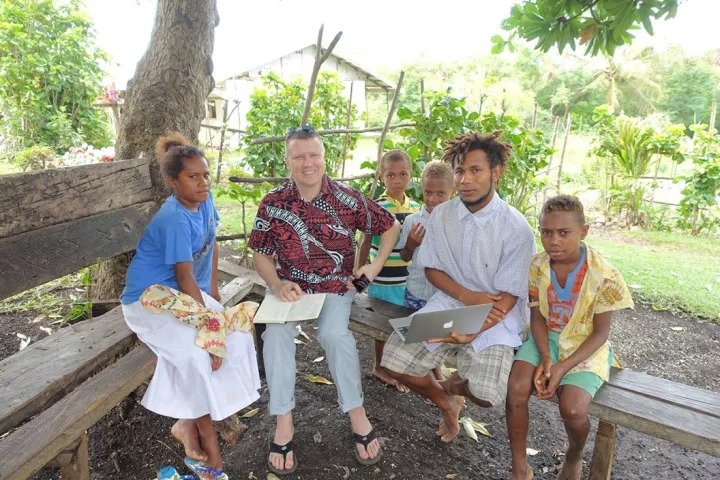 K. David Harrison sits outside with natives of Vanuatu