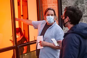 Man wearing mask points to window