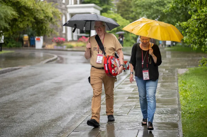 Two people walk in the rain with umbrellas