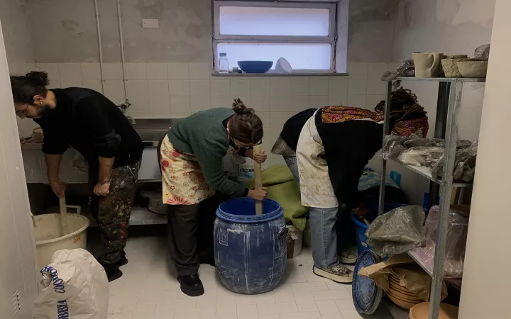 Students stirring liquids in big tubs using pieces of wood