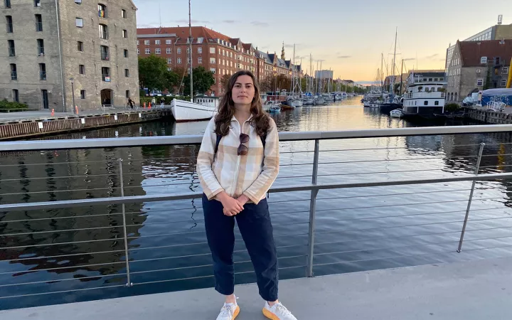 Person standing by rail in front of canal with boats