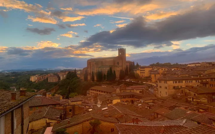 Roofs of buildings with orange-streaked clouds overhead