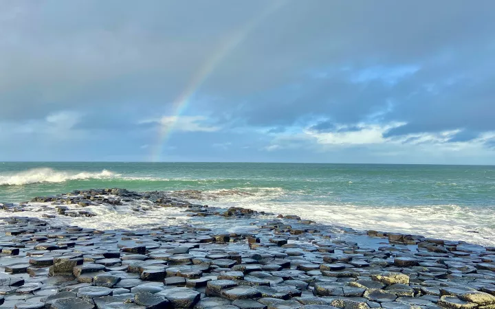 Rainbow over beach covered by circular stones