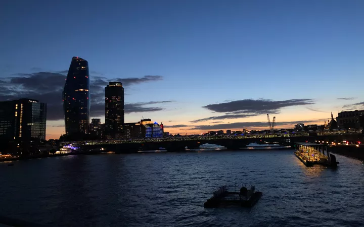 Water with boats at disk, with city lights in background