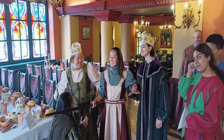 Students wearing costumes and crowns in deserted room with tables