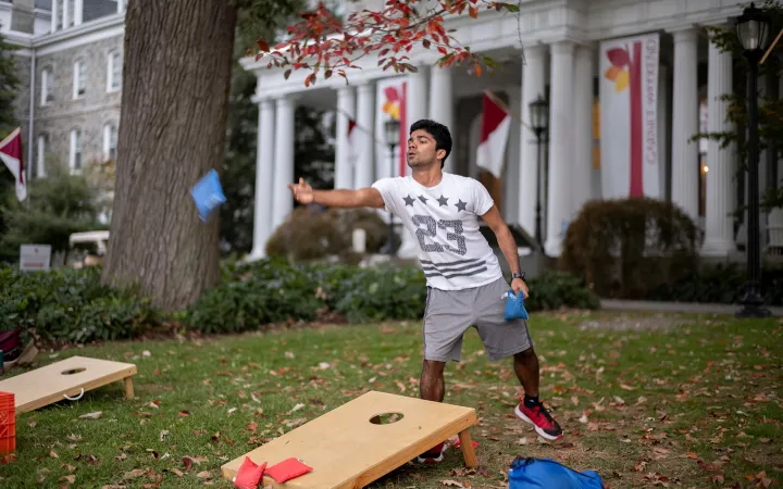 Person plays cornhole outdoors