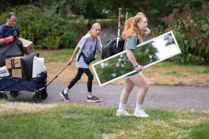 Person carries mirror and person in background pulls wagon