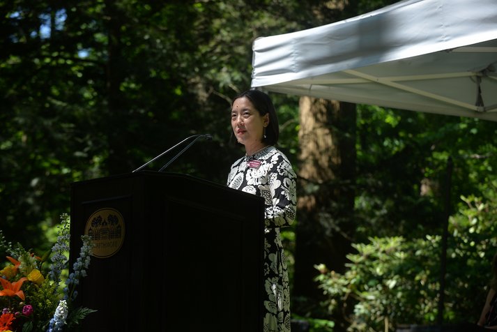 Tomoko Sakomura speaks at podium in outdoor amphitheater