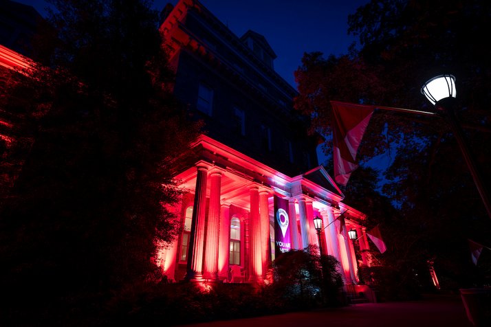 Parrish Hall lit up in red during evening for Alumni Weekend