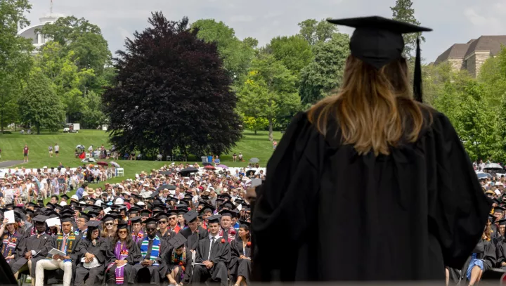 Student walks across stage with crowd in background