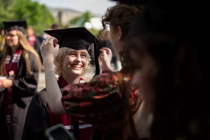 Person fixes graduation cap for friend