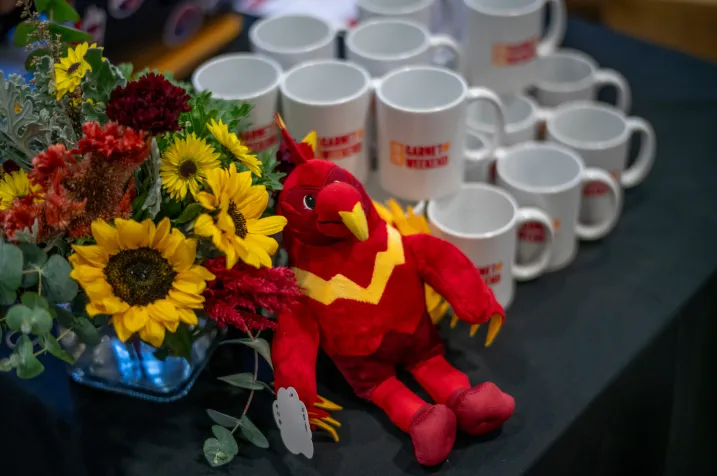 Phineas on table with Garnet Weekend 2024 coffee mugs