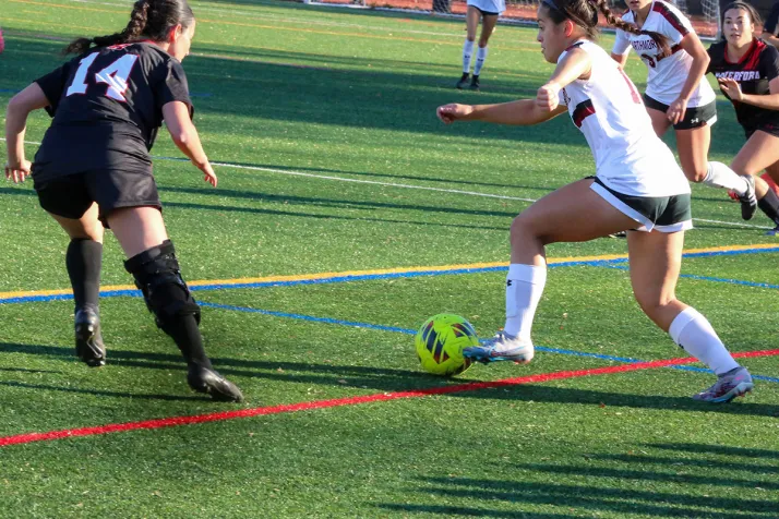 Women's soccer player tries to dribble past defender