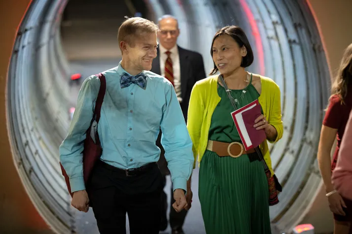 Two people holding hands walk through tunnel