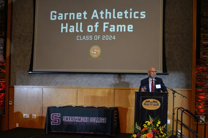 Person stands on stage and addresses audience at athletics hall of fame event