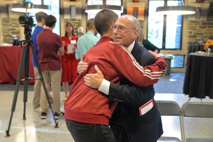 Two people hug at Athletics hall of fame ceremony