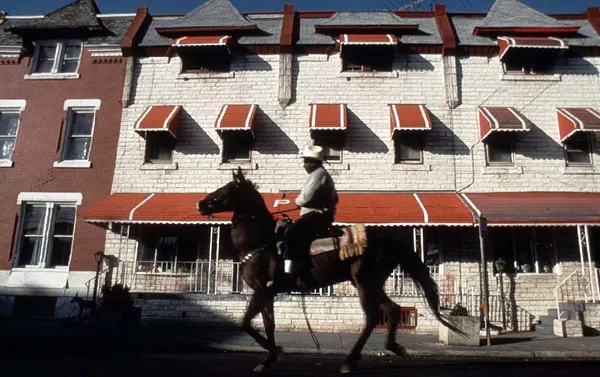 Bob Hill rides his horse down a street of rowhomes in North Philadelphia