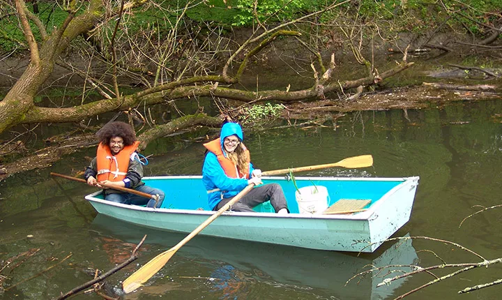 two students in row boat on crum creek