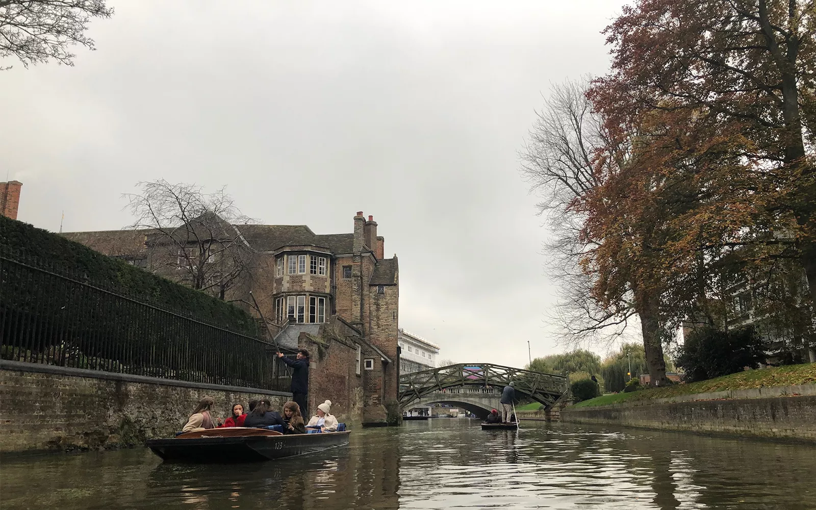 People in boat on river lined with buildings and trees