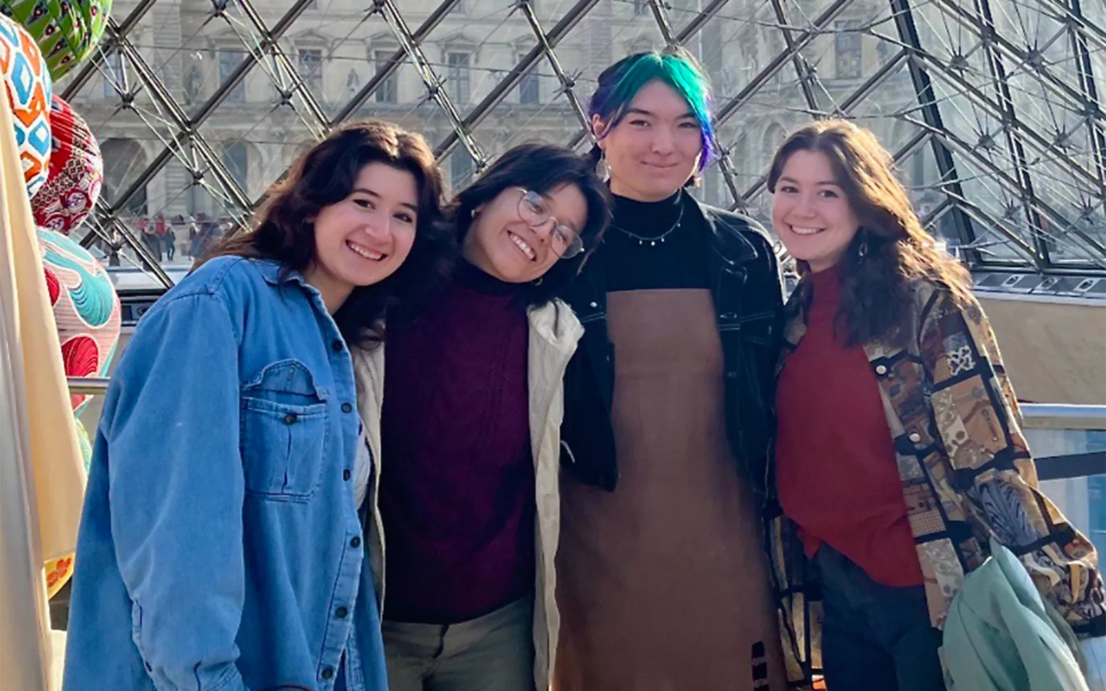 Group of students smiling in front of glass building