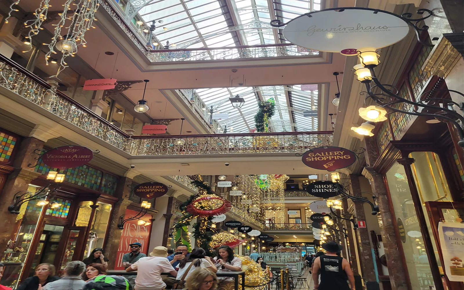 Heads of people walking through shopping mall with string lights and fancy signs