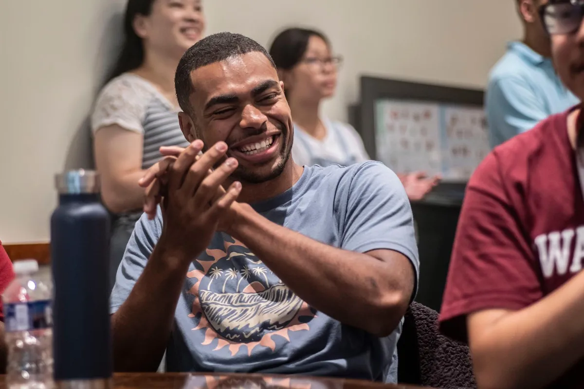 Person seated claps and smiles