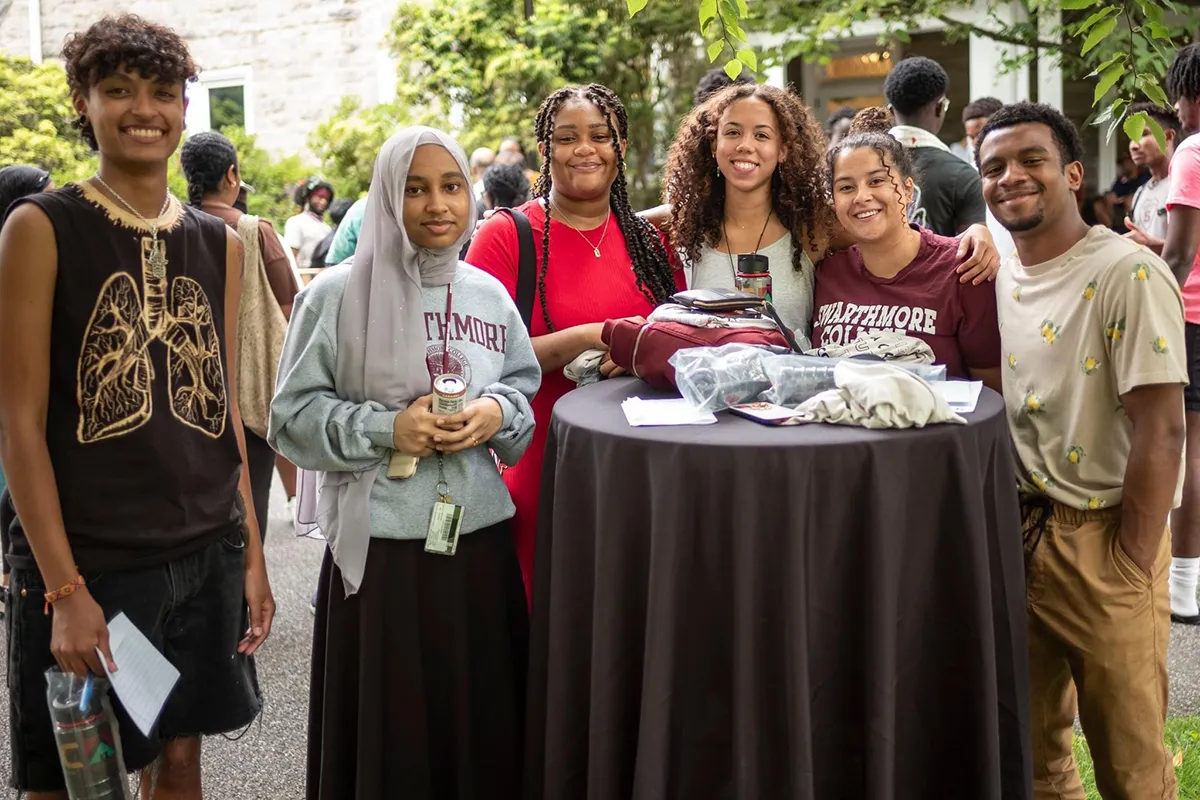 Group of students in circle around table pose for picture