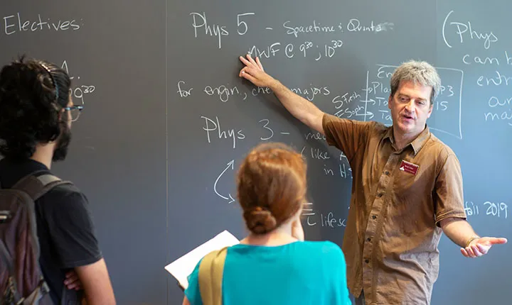 Professor points to blackboard during advising