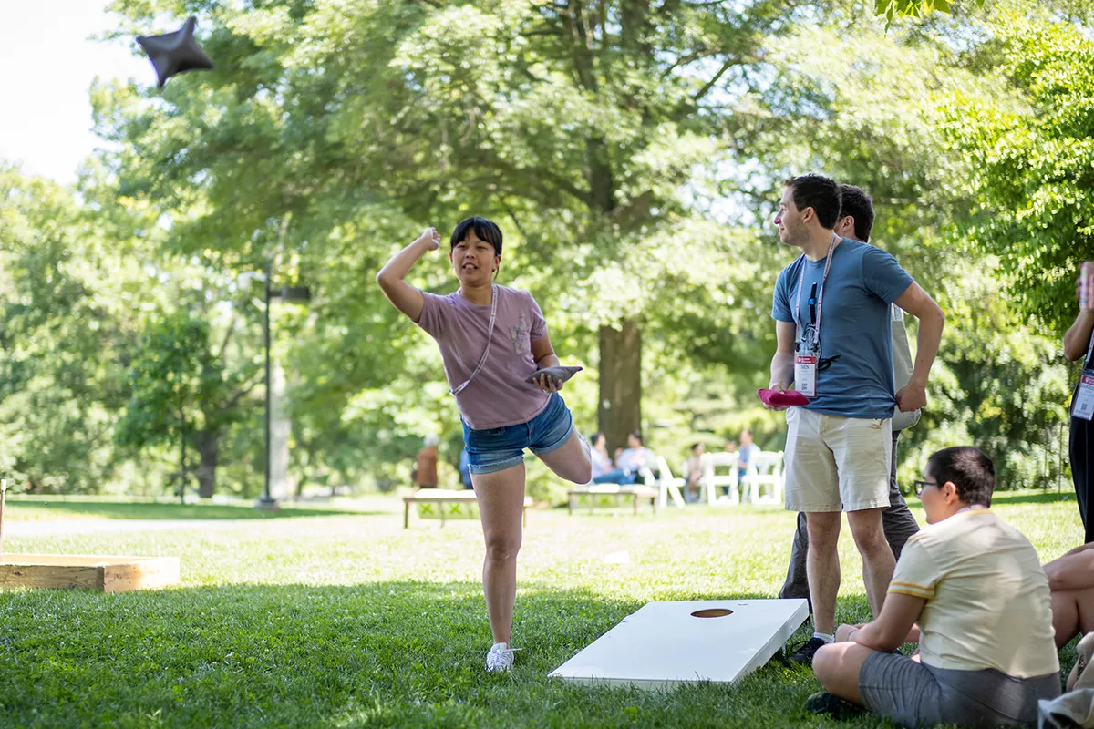 People play conrhole on green lawn