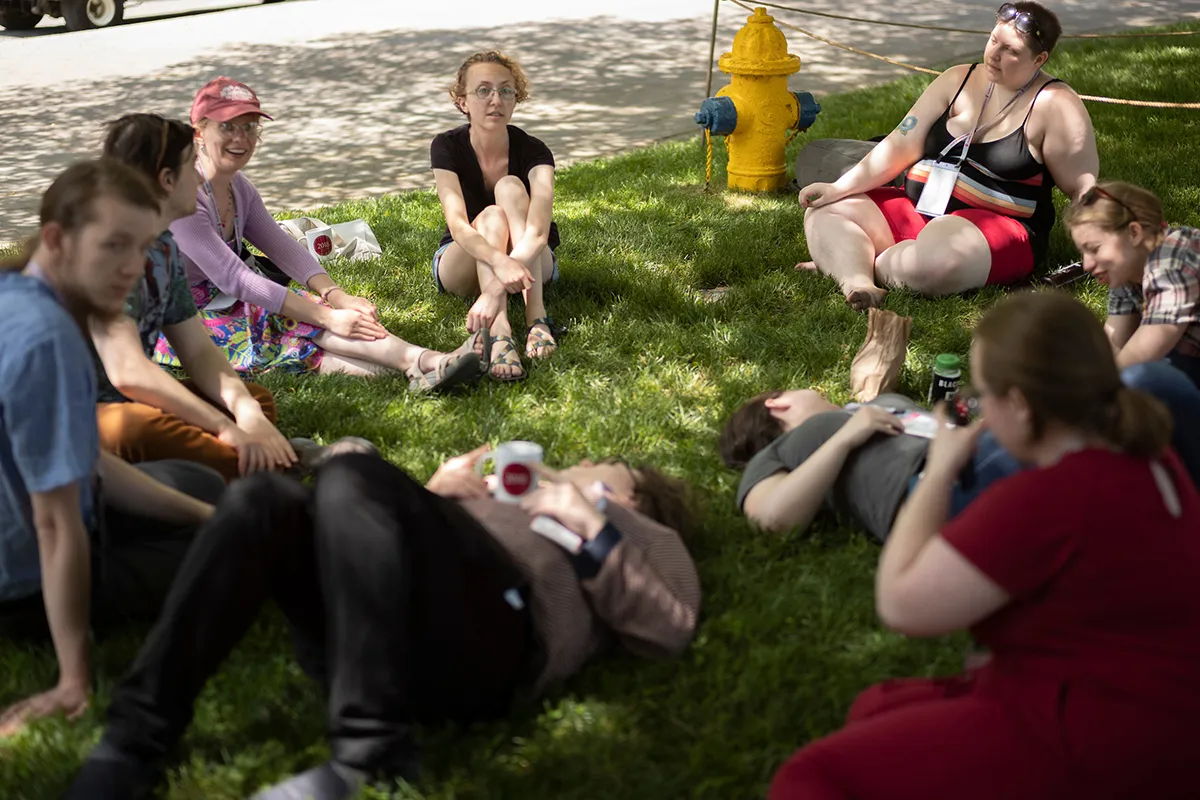 Group of alumni sit in circle on grass