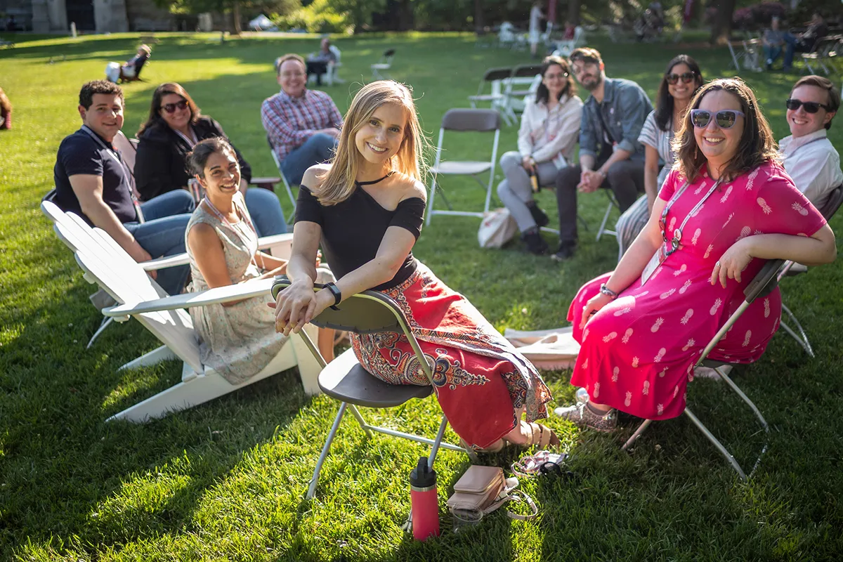 Group of alumni sit in circle on grass