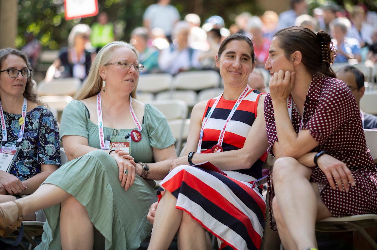 Three alumni sit and have conversation in Scott Outdoor Amphitheater