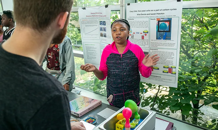 Girl stands in front of poster at science fair