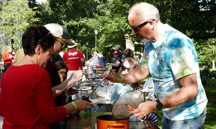 A man serves a woman a bowl of chili