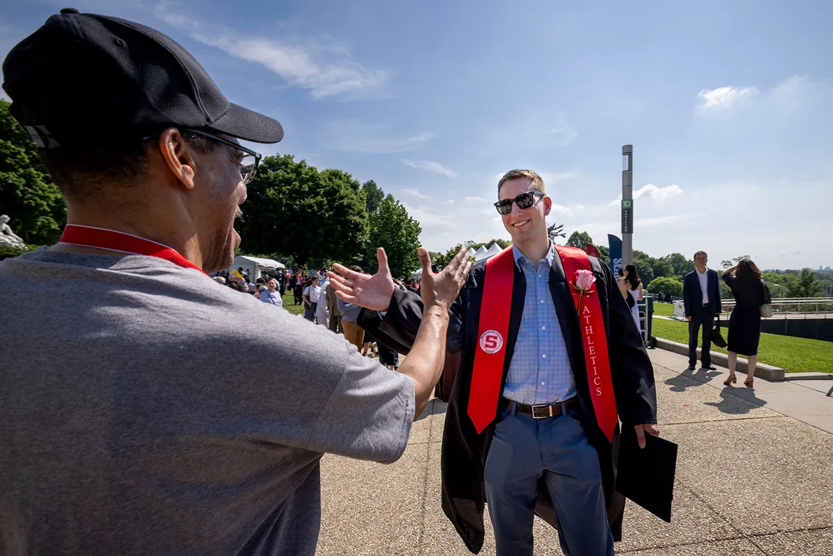 Student shakes hands with staff member after graduating